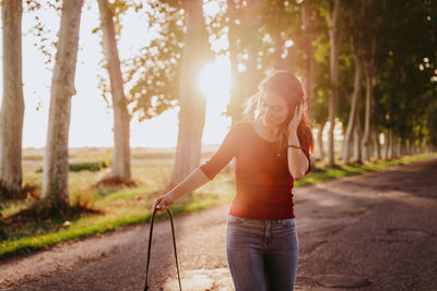 Full length of woman standing by road against trees