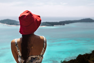 Rear view of woman wearing hat looking at sea against sky