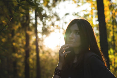 Thoughtful young woman against trees in forest