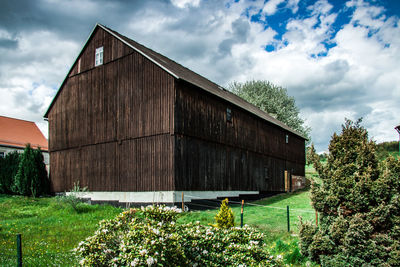 Barn on field by building against sky