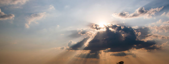 Low angle view of sunlight streaming through clouds