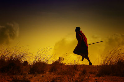 Full length of monk running on field during sunset