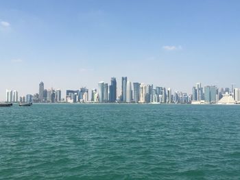Sea by modern buildings against sky in city