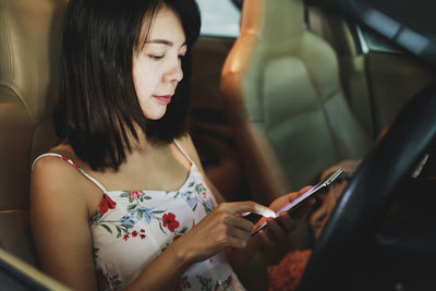 Young woman using mobile phone while sitting in car