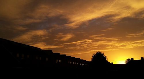 Silhouette houses against sky at sunset