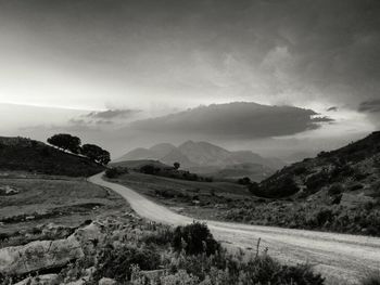 Scenic view of road by mountains against sky