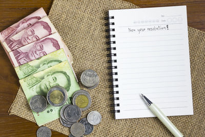 Close-up high angle view of spiral notebook with currency on table