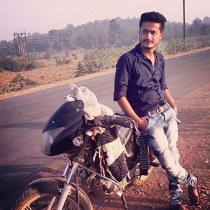 Portrait of young man riding motorcycle on road in city