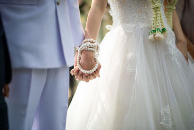 Midsection of bride holding wedding dress