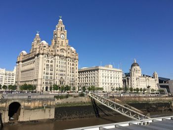 Buildings in city against clear blue sky