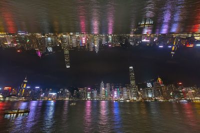 Illuminated buildings by river at night