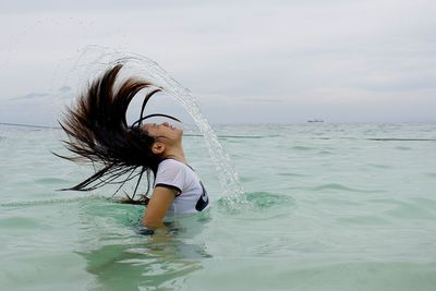 Full length of smiling boy in sea against sky