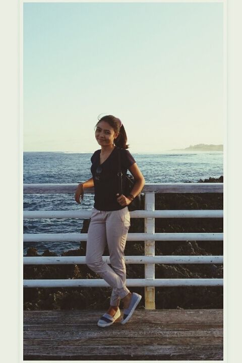 full length, lifestyles, young adult, leisure activity, casual clothing, standing, person, sea, clear sky, front view, young women, looking at camera, transfer print, water, portrait, auto post production filter, copy space, horizon over water