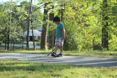Side view of boy holding stick while standing at park