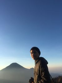 Portrait of man standing against blue sky