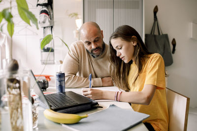 Father assisting daughter doing homework at home