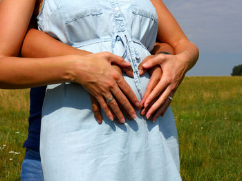 Midsection of woman with arms raised on field