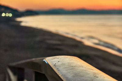 Close-up of wood at beach against sky during sunset