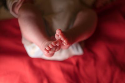 Low section of newborn sleeping on bed at home