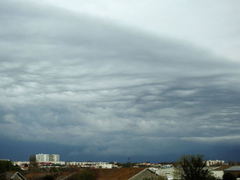 Buildings in city against storm clouds