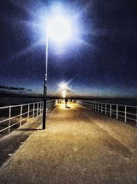 Street lights on road against sky at night