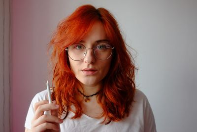 Portrait of redhead woman holding marijuana joint at home