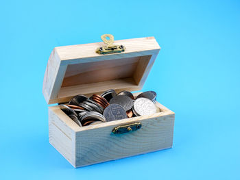 Coins in wooden box against blue background