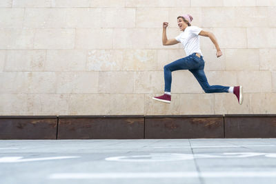Full length side view of man jumping against wall
