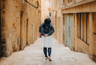 Rear view of woman standing against wall