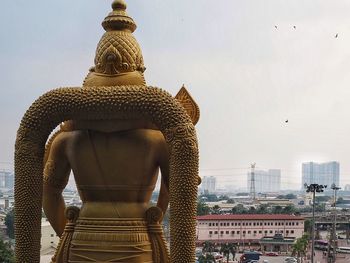 Statue in city against sky