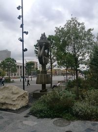 Statue by street against sky in city