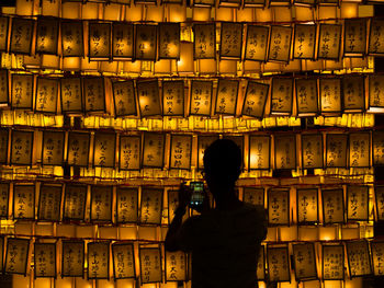 Rear view of man photographing in illuminated room