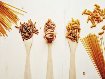 Flat lay with various formats of wholemeal pasta resting on wooden ladles