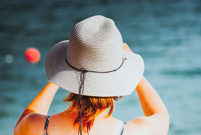 Rear view of woman wearing hat against sea