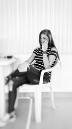 Young woman sitting on chair at home