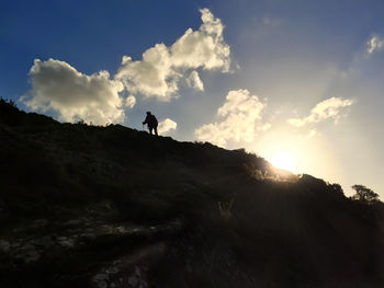 Low angle view of silhouette person on cliff against sky