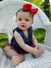 Portrait of cute baby girl sitting on chair at yard