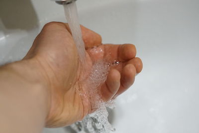 Close-up of person hand holding water in bathroom