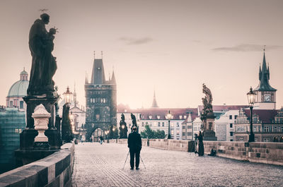 Man statue in city against cloudy sky