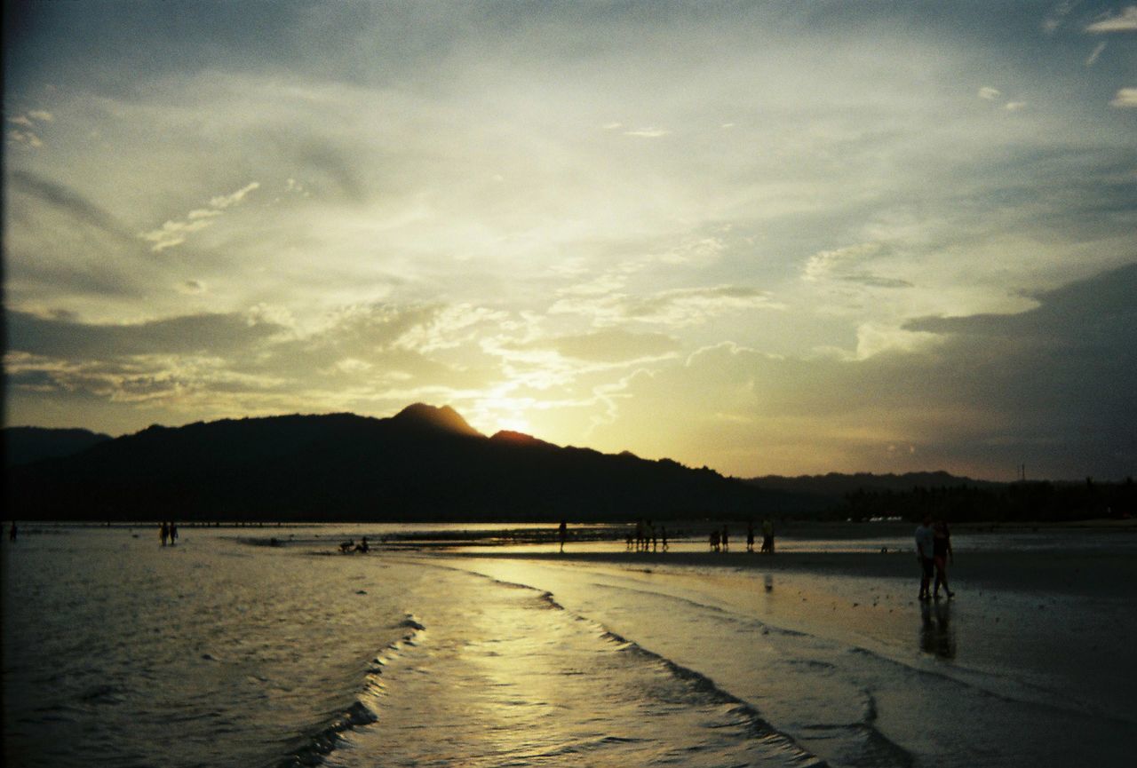 SILHOUETTE PERSON ON BEACH AGAINST SKY