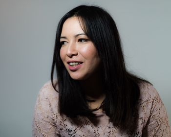 Smiling woman looking away against gray background