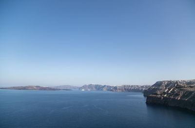 Scenic view of sea and mountains against clear blue sky