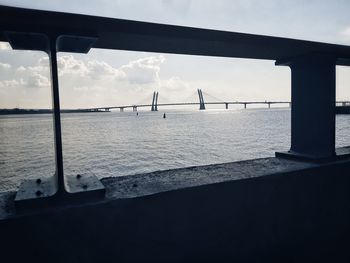 Bridge over calm sea against sky