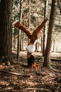 Woman climbing on tree trunk in forest