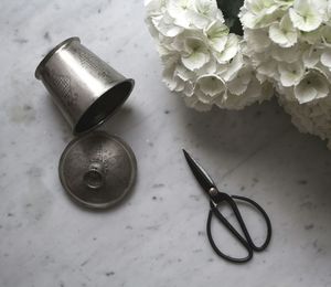 High angle view of scissor by white flower and metal container on floor