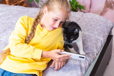 Black and white cat looks at the smartphone screen. teenage girl blogging about pets