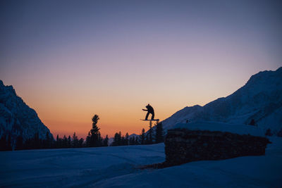 Rear view of man standing on mountain against sky during sunset