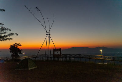 Silhouette trees on field against sky during sunset