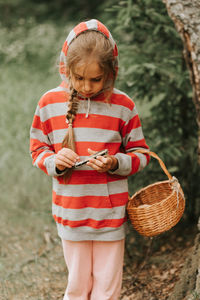 Upset or focused eight year old kid girl mushroom picker is seek for and picking mushrooms