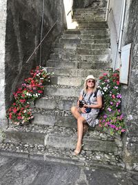 Portrait of woman sitting on staircase against wall